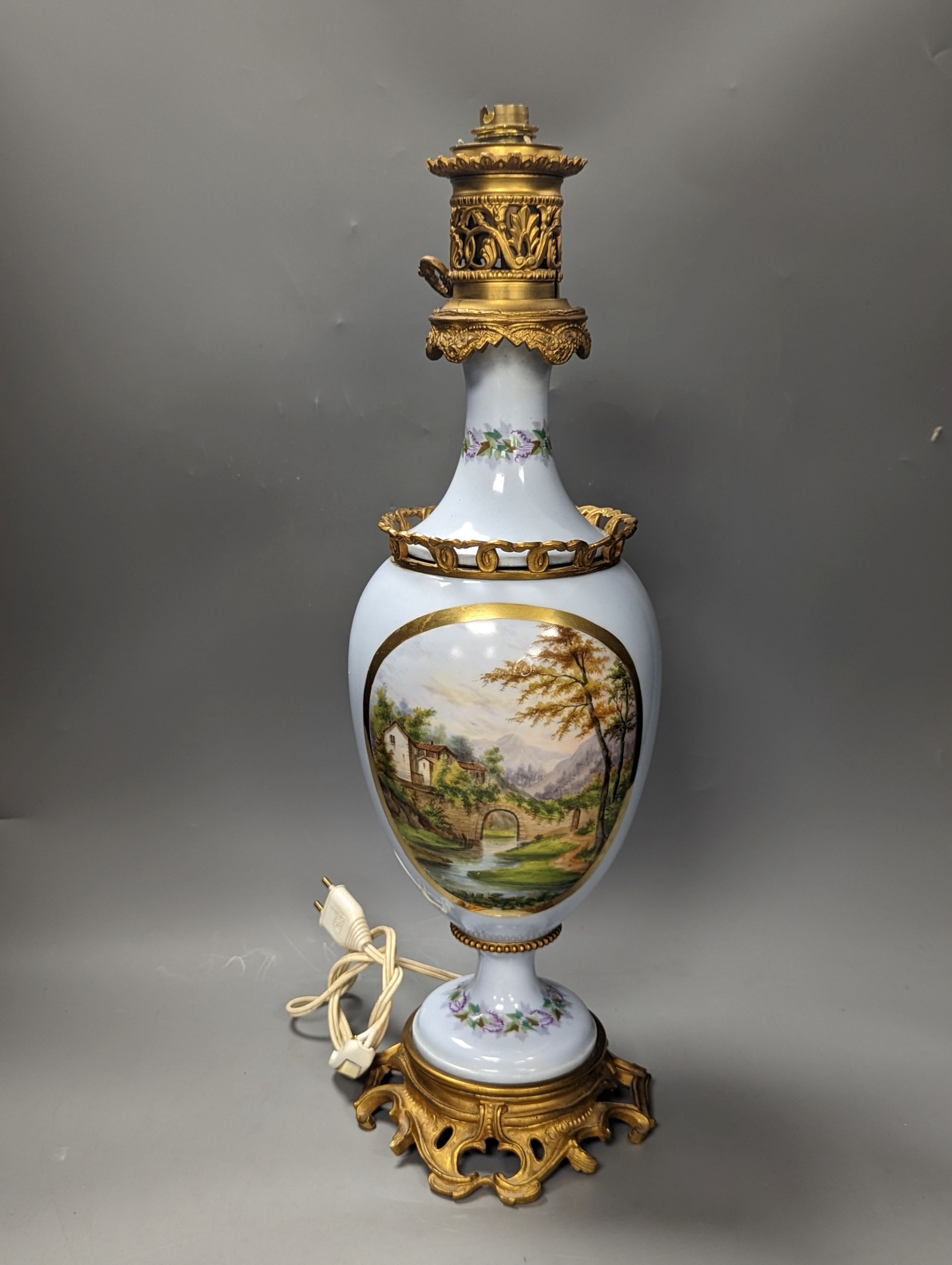 A French 19th century porcelain and ormolu oil lamp (later converted to an eclectic lamp), 54 cms high.